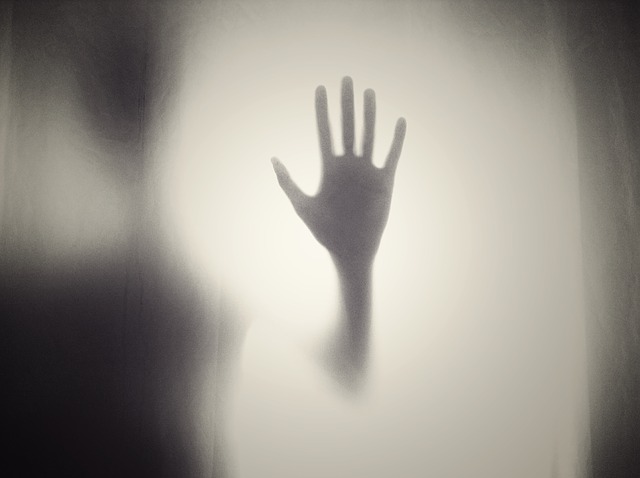 Mysterious shadow figure resting hand on foggy window
