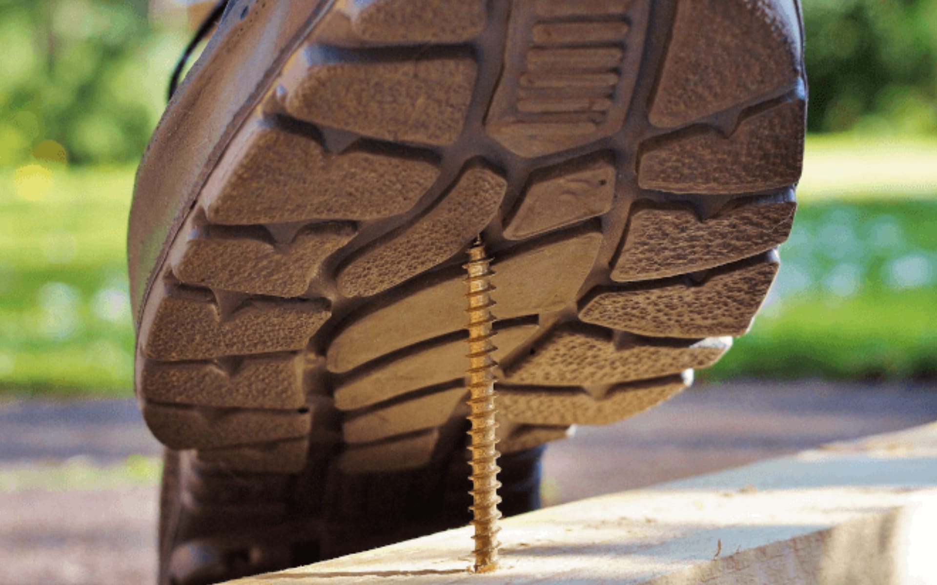 Work boot about to step on exposed screw nail (metaphor for risk mitigation)